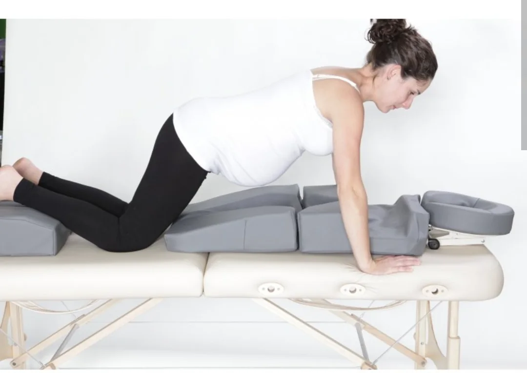 A pregnant woman lying face down on a maternity cushion