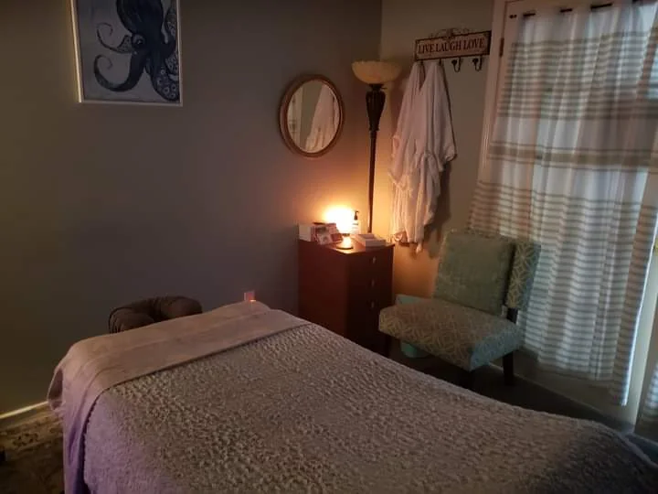 Treatment room with a massage table and warm lamp light